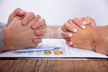 What to expect when getting divorced - two hands on table with rings on table between them.